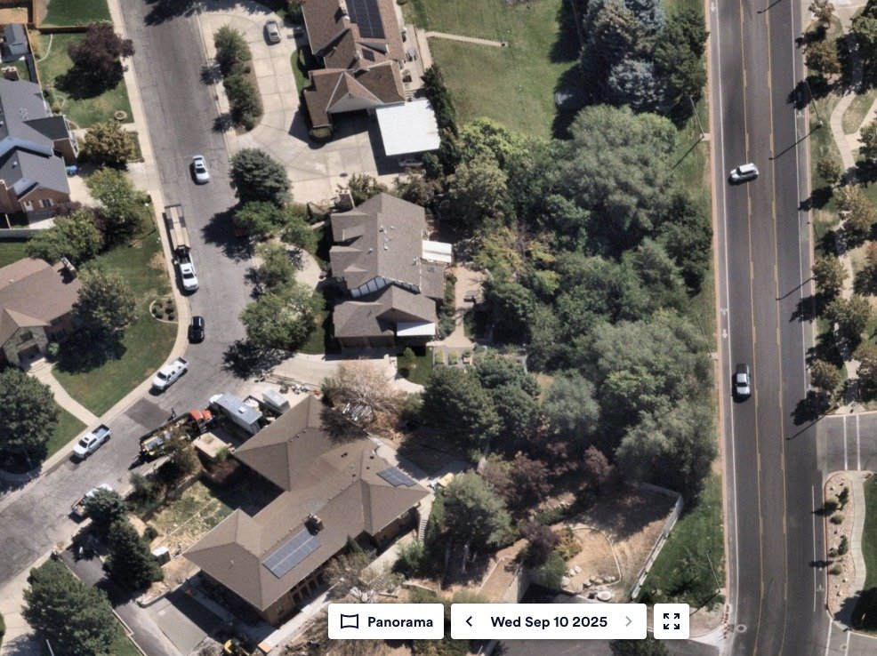 Aerial panorama imagery dated Wed Sep 10 2025 showing the residential block north of UVU, the wooded strip along the roadway, and a white compact vehicle on the street