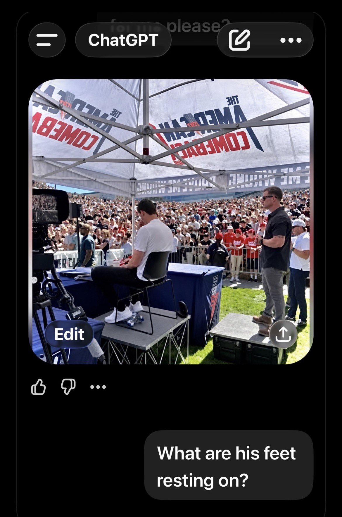 Screenshot of a ChatGPT conversation showing a wide photo of the UVU tent, the speaker platform, and a man standing on a separate riser, with the typed question 'What are his feet resting on?'