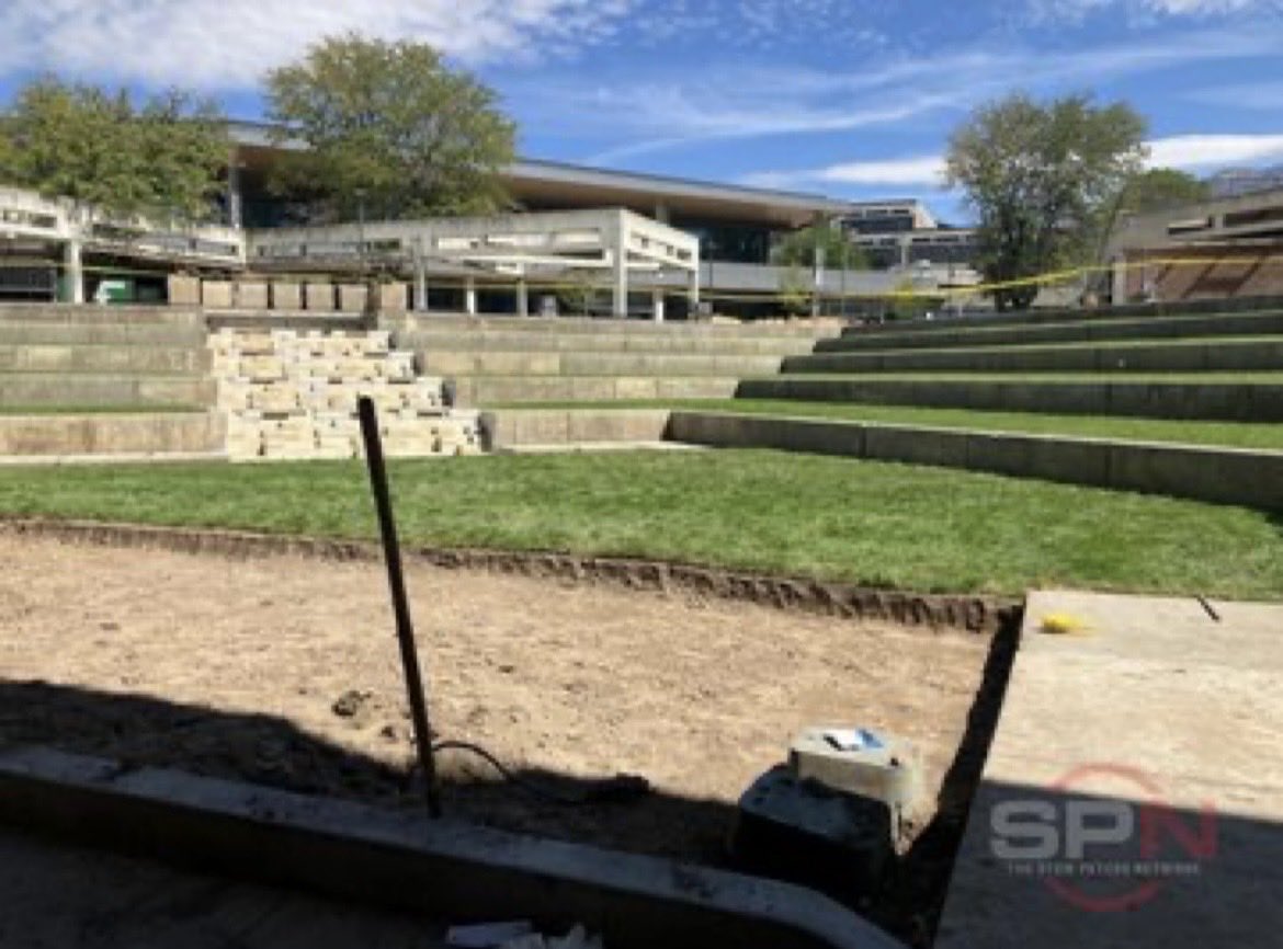 UVU Sorensen Center courtyard with a wide strip of bare excavated soil across the foreground and a clean cut sod edge against the surviving lawn