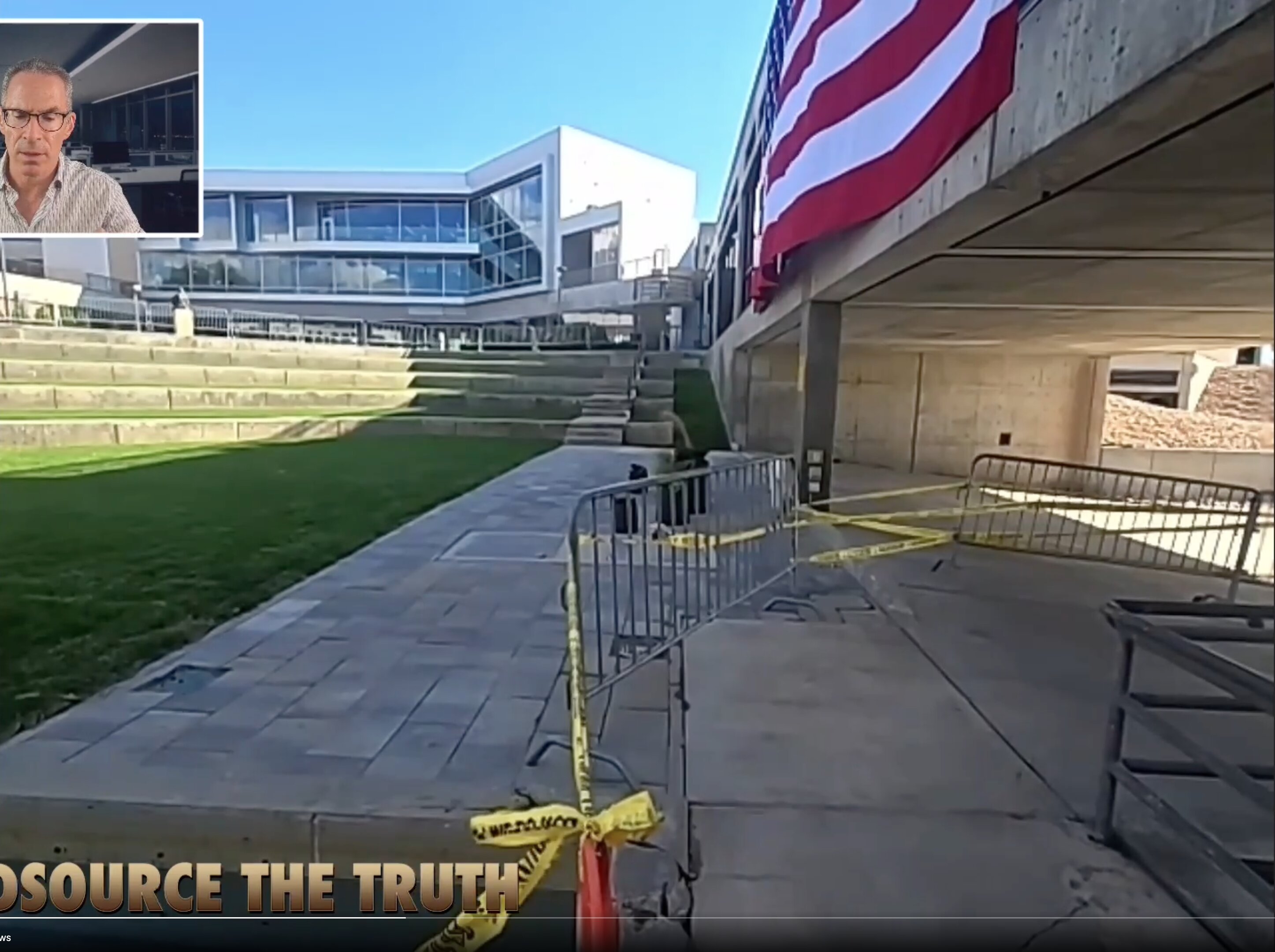 This is a wide-angle, eye-level exterior shot of a modern institutional or corporate campus plaza featuring a concrete amphitheater and a large building with extensive glazing.